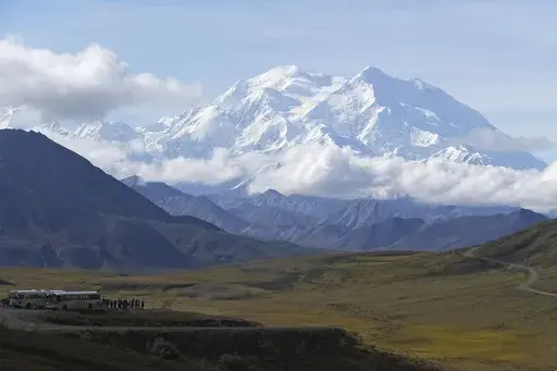 Sightseeing buses and tourists are seen at a pullout popular for taking in views of North America's tallest peak, Denali, in Denali National Park and Preserve, Alaska, Aug. 26, 2016. Two climbers awaited rescue near the peak of North America’s tallest mountain Wednesday, May 29, 2024, a day after they and a third climber in their team requested help after summiting Denali during the busiest time of the mountaineering season, officials at Denali National Park and Preserve said. (AP Photo/Becky 