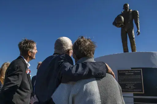 Apollo 13 astronaut Fred Haise Jr., center, hugs sculptor Mary Ott Tremmel Davidson as her statue honoring Haise is unveiled at Biloxi Beach in Biloxi, Miss., Sunday, Feb. 13, 2022. The original ceremony, planned for the 50th anniversary of Apollo 13 in April 2020, was canceled because of COVID-19. Sunday’s event went on despite the death of Haise’s wife, Patt, less than a week before. (Hannah Ruhoff/The Sun Herald via AP)