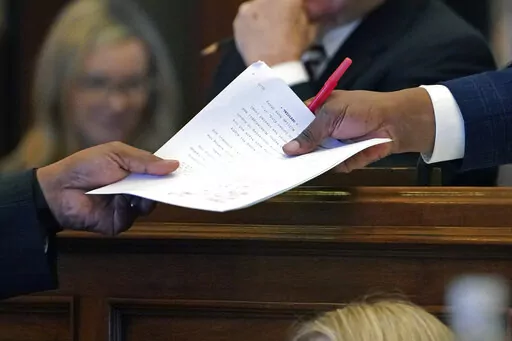 Mississippi Senate Press Secretary Arnold Lindsay, right, receives a resolution from a senator at the Mississippi Capitol in Jackson, Miss., Wednesday, Feb. 23, 2022. (AP Photo/Rogelio V. Solis)