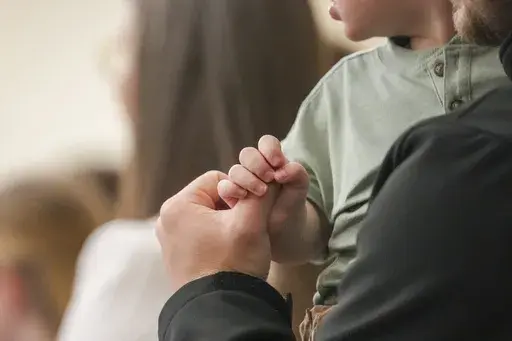 A child holds a man's finger during a service at Community Church of Seminole, Sunday, Feb. 23, 2025, in Seminole, Texas. (AP Photo/Julio Cortez)