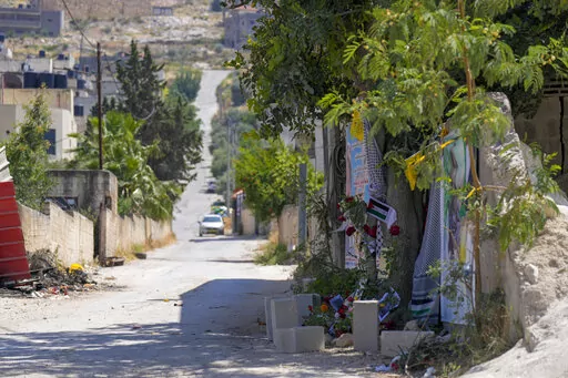 Flowers, flags and other memorabilia create a makeshift memorial at the site where  veteran Palestinian-American reporter Shireen Abu Akleh was shot and killed, in the West Bank city of Jenin, May 19, 2022. Almost two weeks after the death of Abu Akleh, a reconstruction by The Associated Press lends support to assertions from both Palestinian authorities and Abu Akleh's colleagues that the bullet that cut her down came from an Israeli gun. (AP Photo/Majdi Mohammed)
