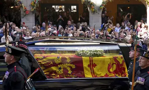 Members of the public look on a Queen Elizabeth II's coffin makes its way from the Palace of Holyroodhouse to St Giles' Cathedral, in Edinburgh, Monday, Sept. 12, 2022. King Charles III arrived in Edinburgh on Monday to accompany his late mother’s coffin on an emotion-charged procession through the historic heart of the Scottish capital to the cathedral where it will lie for 24 hours to allow the public to pay their last respects. (Andrew Milligan/Pool Photo via AP)
