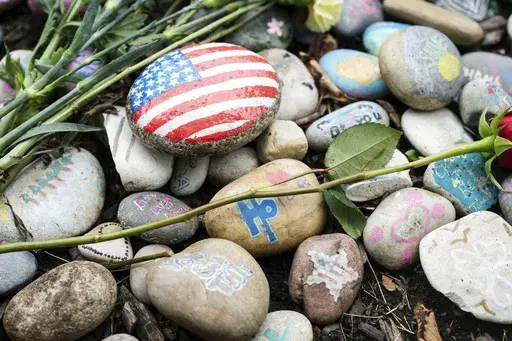 The temporary memorial for the Highland Park shooting victims, Katie Goldstein, Irina McCarthy, Kevin Michael McCarthy, Stephen Straus, Jacki Lovi Sundheim, Nicolás Toledo and Eduardo Uvaldo, is seen near 1707 St. Johns Avenue in Highland Park, Ill., Thursday, July 4, 2024, two years after a mass shooting at the parade. (Pat Nabong/Chicago Sun-Times via AP)