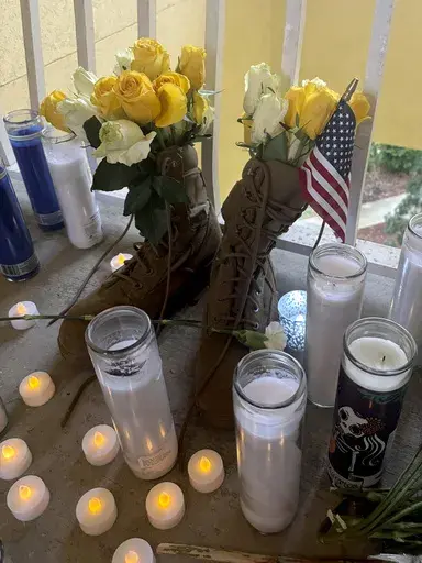 A small shrine is pictured Monday, May 13, 2024, in Fort Walton Beach, Fla. at the door of an apartment where a Florida deputy shot and killed Senior Airman Roger Fortson. The shrine includes a long wooden plank, anchored by two sets of aviator wings and a black marker to leave thoughts, a Stella Artois, and combat boots and an American Flag. As the unit takes a day to grieve and prepare for a funeral Friday, May 17, questions remain about the shooting. (AP Photo)