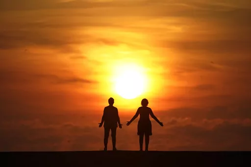 In this Sept. 19, 2020 file photo, a couple stands on a jetty as the sun rises over the Atlantic Ocean in Bal Harbour, Fla. Millions of Americans struggle with mental illnesses. One way to do so is by setting up a trust. An important question to ask is how a trust will affect their loved one’s eligibility for government benefits. Other factors to explore include the best trustees to appoint and whether their estate plan is clear and easy to follow. (AP Photo/Wilfredo Lee, File)