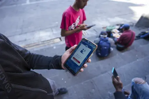 Venezuelan migrant Yender Romero shows the U.S. Customs and Border Protection (CBP) One app on his cell phone, which he said he used to apply for asylum in the U.S. and is waiting on an answer, at a migrant tent camp outside La Soledad church in Mexico City, Jan. 20, 2025. (AP Photo/Fernando Llano, File)
