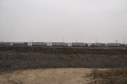 Trucks, carrying humanitarian supplies for the Gaza Strip, wait in line on the Egyptian side, at the Kerem Shalom Crossing border as seen from southern Israel, Thursday, April 25, 2024. A persistent breakdown in law and order is rendering an aid route in south Gaza unusable, the UN and NGOs say, days after Israel's military said it would pause combat there to help aid reach desperate Palestinians. (AP Photo/Leo Correa, File)