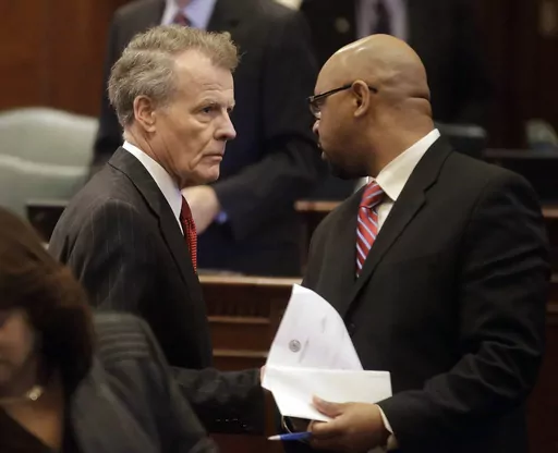 FILE -Illinois Speaker of the House Michael Madigan, D-Chicago, left, speaks with Illinois Rep. Thaddeus Jones, D-Calumet, right, while on the House floor after adjoining veto session, Thursday, Nov. 7, 2013 in Springfield Ill. Officials in a suburban Chicago community have issued municipal citations to a Hank Sanders, a local news reporter for what they say are persistent contacts with city officials for comment on treacherous fall flooding. Sanders continued to call and email city employees, d