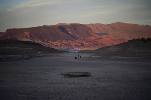 A formally sunken boat sits on cracked earth hundreds of feet from what is now the shoreline on Lake Mead at the Lake Mead National Recreation Area, Monday, May 9, 2022, near Boulder City, Nev. Lake Mead is receding and Sin City is awash with mob lore after a second set of human remains emerged within a week from the depths of the drought-stricken Colorado River reservoir just a short drive from the Las Vegas Strip.  (AP Photo/John Locher)