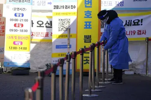 A health worker wearing protective gear prepares for visitors in the sub-zero temperatures at a temporary screening clinic for the coronavirus in Seoul, South Korea, Friday, Jan. 14, 2022. (AP Photo/Lee Jin-man)