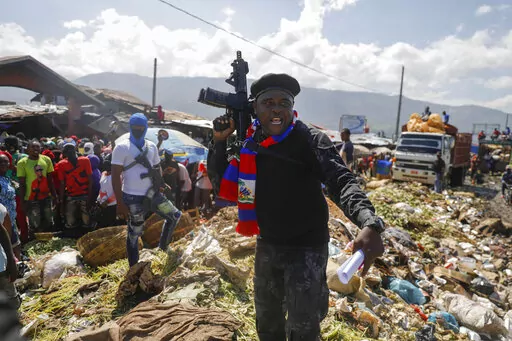 Barbecue, the leader of the "G9 and Family" gang, stands next to garbage to call attention to the conditions people live in as he leads a march against kidnapping through La Saline neighborhood in Port-au-Prince, Haiti, Friday, Oct. 22, 2021. Haiti Prime Minister Ariel Henry and 18 top-ranking officials have requested on the second week of Oct. 2022, the immediate deployment of foreign armed troops as gangs and protesters paralyze the country. (AP Photo/Odelyn Joseph, File)