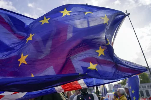A Union flag waves behind a European Union flag, outside the Houses of Parliament, in London, Wednesday, Oct. 19, 2022. The British government on Sunday, Nov. 20, 2022 denied a report it is seeking a “Swiss-style” relationship with the European Union that would remove many of the economic barriers erected by Brexit — even as it tries to repair ties with the bloc after years of acrimony. (AP Photo/Alberto Pezzali, File)