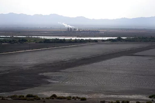 A dried up portion of the Salton Sea stretches out with a geothermal power plant in the distance in Niland, Calif., Thursday, July 15, 2021. Demand for electric vehicles has shifted investments into high gear to extract lithium from geothermal wastewater around the rapidly shrinking body of water. The ultralight metal is critical to rechargeable batteries. (AP Photo/Marcio Jose Sanchez, File)