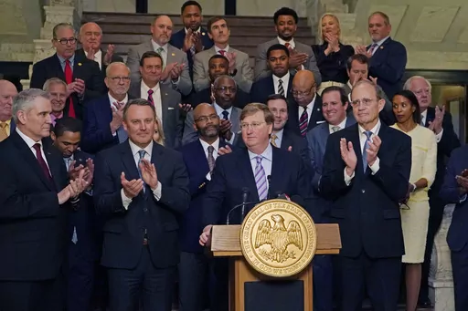 Mississippi Republican Gov. Tate Reeves, center, receives applause from House Speaker Jason White, R-West, left, and Republican Lt. Gov. Delbert Hosemann, right, as well as a bipartisan group of legislators, for pursing a package of state incentives to support a plan by Amazon Web Services to build two data centers in the central part of the state, Thursday, Jan. 25, 2024, during the celebratory announcement at the Mississippi Capitol in Jackson, Miss. (AP Photo/Rogelio V. Solis)