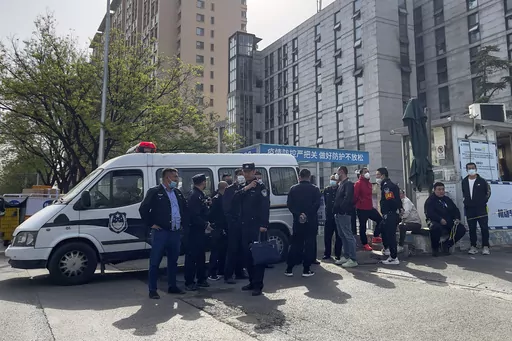 Police officers and security guards gather outside the barricaded hospital following a fire at a hospital in Beijing, Wednesday, April 19, 2023. More than a dozen people have died in a fire at a Beijing hospital that forced the evacuation of dozens of patients on Tuesday, Chinese state media reported. (AP Photo/Andy Wong)