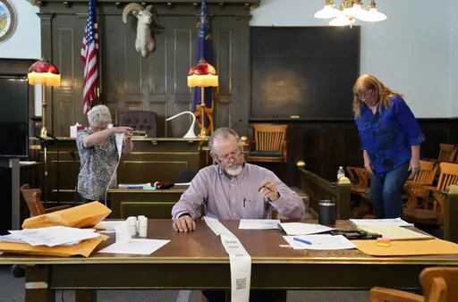 Esmeralda County Commissioner Ralph Keyes, center, works on a hand recount of votes with others, June 24, 2022, in Goldfield, Nev.  An AP survey shows the majority of candidates running this year for the state posts that oversee elections oppose the idea of hand counting ballots, a laborious and error-prone process that has gained favor among Republicans who have been inundated with unfounded voting machine conspiracy theories.  (AP Photo/John Locher, File)