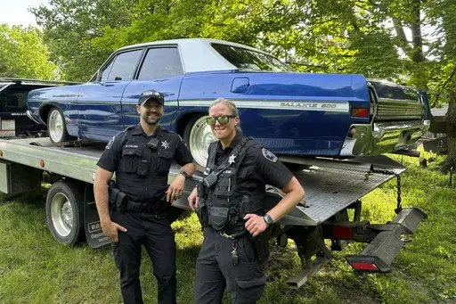 This photo provided by the Ingham County Sheriff's Office shows two deputies near a stolen car that was recovered Tuesday, June 4, 2024, in Ingham County, Mich. The car had a flat tire when it was stolen from the side of a highway in May. It had been restored by the Make-A-Wish Foundation. (Ingham County Sheriff's Office via AP)