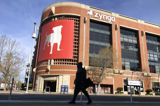 A pedestrian walks in front of a sign at Zynga in San Francisco, Tuesday, March 16, 2021. Take-Two Interactive, maker of Grand Theft Auto and Red Dead Redemption, is buying Zynga, maker of FarmVille and Words With Friends, in a cash-and-stock deal with an enterprise value of about $12.7 billion. Take-Two said Monday, Jan. 10, 2022, it anticipates $100 million in annual cost savings. (AP Photo/Jeff Chiu, File)