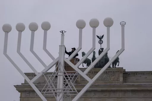 Rabbi Yehuda Teichtal, center, inspects a giant Hanukkah Menorah, set up by the Jewish Chabad Educational Center ahead of the Jewish Hanukkah holiday, in front of the Brandenburg Gate at the Pariser Platz in central Berlin, Germany, Wednesday, Dec. 6, 2023. Holocaust survivors from around the globe will mark the start of the fifth day of Hanukkah together with a virtual ceremony as worries grow among Jews worldwide about the Israel-Hamas war and a spike of antisemitism in Europe, the United Stat