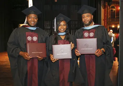 In this photo provided by Mississippi State University - Meridian Office of Public Affairs, Ja'Coby Cole, left, his sister Iesha Gully and their father Commondre Cole, right, show their diploma covers, on Thursday, May 12, 2022, during the school's commencement at the MSU Riley Center in Meridian, Miss. Each of the three earned a master's degree in education. (Lisa Sollie/Mississippi State University - Meridian via AP)