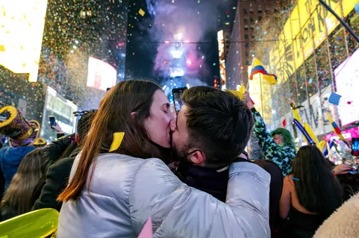 Irene Mayoral, left and Gerald Nuell of Spain kiss as they celebrate in Times Square in New York Saturday, Jan. 1, 2022, as they attend New Year's Eve celebrations. The couple became engaged Friday. (AP Photo/Craig Ruttle)