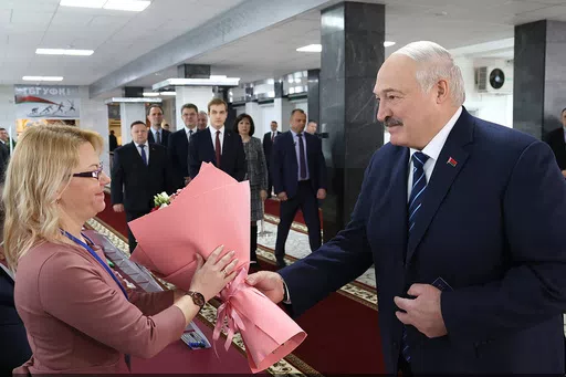 In this photo provided by the Belarusian Presidential Press Service, Belarus President Alexander Lukashenko, right, presents flowers to an election commission official ahead of voting at a polling station, in Minsk, Belarus, Sunday, Feb. 25, 2024. Lukashenko was believed a few years ago to be considering whether to lead the new body after stepping down, but his calculus has apparently changed, and he announced on Sunday that he will run in next year's presidential election. (Belarusian President