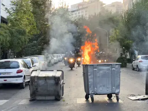 In this Tuesday, Sept. 20, 2022, photo taken by an individual not employed by the Associated Press and obtained by the AP outside Iran, a trash bin is burning as anti-riot police arrive during a protest over the death of a young woman who had been detained for violating the country's conservative dress code, in downtown Tehran, Iran. Iran faced international criticism on Tuesday over the death of a woman held by its morality police, which ignited three days of protests, including clashes with se
