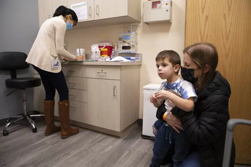 Ilana Diener holds her son, Hudson, 3, during an appointment for a Moderna COVID-19 vaccine trial in Commack, N.Y. on Nov. 30, 2021. Parents hoping to get their youngest children vaccinated against COVID-19 have some encouraging news. Pfizer said Monday, May 23, 2022, that three doses of its vaccines offers strong protection to those under 5. That news comes a month after Moderna said it would ask regulators to OK its two shot regimen for the youngest kids. (AP Photo/Emma H. Tobin, File)