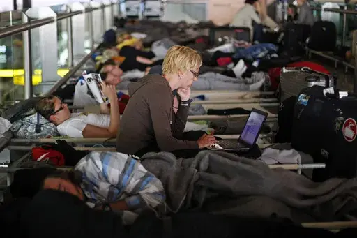 Passengers waiting for a flight to Helsinki rest at Lisbon's international Portela Airport on May 10, 2010, as flights were disrupted due to an ash cloud drifting over from a volcano in Iceland that caused major air travel chaos. (AP Photo/Francisco Seco, File)