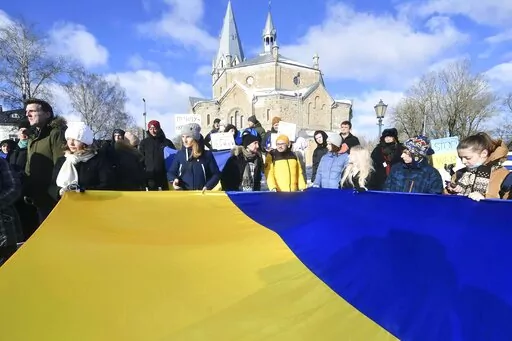 People hold a huge Ukrainian national flag during a protest in support of Ukraine in front of the Russian General Consulate in Narva, Estonia, Saturday, Feb. 26, 2022. Russian troops stormed toward Ukraine's capital Saturday, and street fighting broke out as city officials urged residents to take shelter. (AP Photo/Sergei Stepanov)