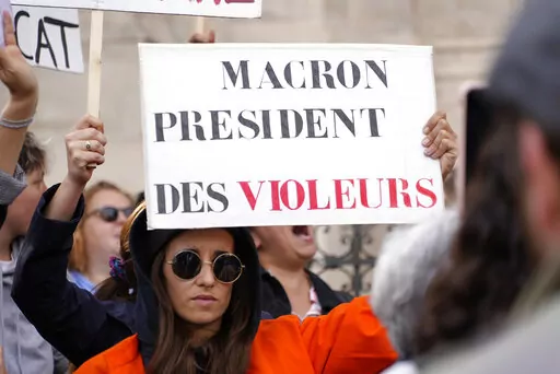 A woman shows a poster reading "Macron, President of rapists" during a demonstration organized by a feminist association called the Observatory on Sexual and Gender-based violence in politics, Tuesday, May 24, 2022 in Paris. Rape accusations against a newly named French government minister have galvanized a movement aimed at exposing sexual misconduct in French politics and encouraging women to speak out against abusers. (AP Photo/Nicolas Garriga)