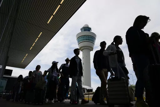 Travelers wait in long lines outside the terminal building to check in and board flights at Amsterdam's Schiphol Airport, Netherlands, Tuesday, June 21, 2022. After two years of pandemic restrictions, travel demand is back with a vengeance but airlines and airports that slashed jobs during the depths of the COVID-19 crisis are struggling to keep up. With the busy summer tourism season underway in Europe, passengers are encountering chaotic scenes at airports, including lengthy delays, canceled f