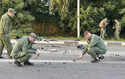 In this handout photo taken from video released by Investigative Committee of Russia on Sunday, Aug. 21, 2022, investigators work on the site of explosion of a car driven by Daria Dugina outside Moscow. Daria Dugina, the daughter of Alexander Dugin, the Russian nationalist ideologist often called "Putin's brain", was killed when her car exploded on the outskirts of Moscow, officials said Sunday. The Investigate Committee branch for the Moscow region said the Saturday night blast was caused by a 