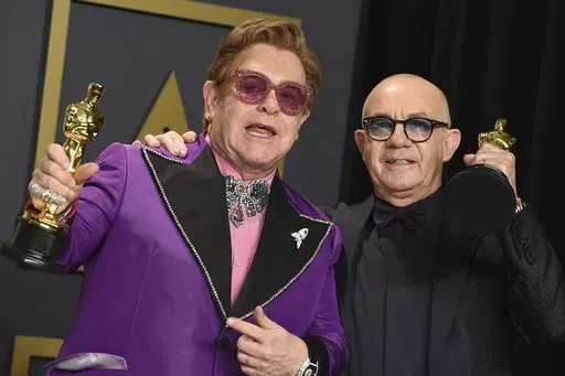 Elton John, left, and Bernie Taupin, winners of the award for best original song for "(I'm Gonna) Love Me Again" from "Rocketman", pose in the press room at the Oscars on Sunday, Feb. 9, 2020, in Los Angeles. (Photo by Jordan Strauss/Invision/AP, File)
