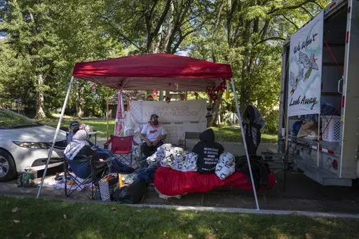 Protesters, including Mike Madanat, center in the white t-shirt, gather near Ohio Democratic Rep. Greg Landsman's Cincinnati residence, Monday, Oct. 7, 2024. (AP Photo/Carolyn Kaster)