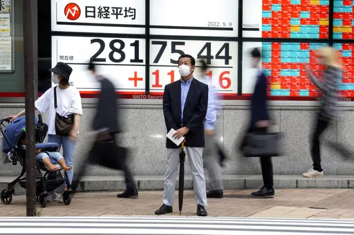 A person wearing a protective mask stands in front of an electronic stock board showing Japan's Nikkei 225 index at a securities firm Friday, Sept. 9, 2022, in Tokyo. Asian benchmarks rose Friday, cheered by gains on Wall Street as comments from the Federal Reserve chairman assured markets on the expected rate rise.(AP Photo/Eugene Hoshiko)