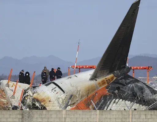 Experts from the U.S. National Transportation Safety Board (NTSB) and joint investigation team between the U.S. and South Korea check the site of a plane crash at Muan International Airport in Muan, South Korea, Tuesday, Dec. 31, 2024. (Son Hyung-joo/Yonhap via AP)