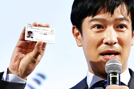 Japanese actor Masato Sakai shows a sample of My Number card during a promotional event in Tokyo on March 8, 2021. Japan has stepped up its push to catch up on digitization by telling a reluctant public they have to sign up for digital IDs or possibly lose access to their public health insurance. (Kyodo News via AP)