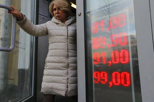 In this Feb. 24, 2022, photo, a woman leaves an exchange office with screen showing the currency exchange rates of U.S. Dollar and Euro to Russian Rubles in Moscow, Russia. The harsh sanctions imposed on Russia and the resulting crash of the ruble have the Kremlin scrambling to keep the country's economy running. For Russian President Vladimir Putin, that means finding workarounds to the economic blockade even as his forces continue to invade Ukraine. (AP Photo/Alexander Zemlianichenko Jr., File