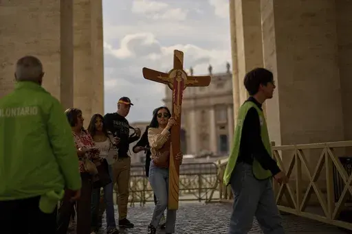A faithful carries a cross in St. Peter's Square at the Vatican, Friday, March 7, 2025. (AP Photo/Francisco Seco)