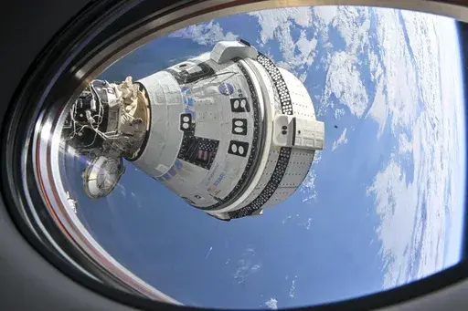 This photo provided by NASA shows Boeing's Starliner spacecraft which launched astronauts Butch Wilmore and Suni Williams to the International Space Station docked to the Harmony module's forward port on July 3, 2024, seen from a window on the SpaceX Dragon Endeavour spacecraft docked to the adjacent port. (NASA via AP)