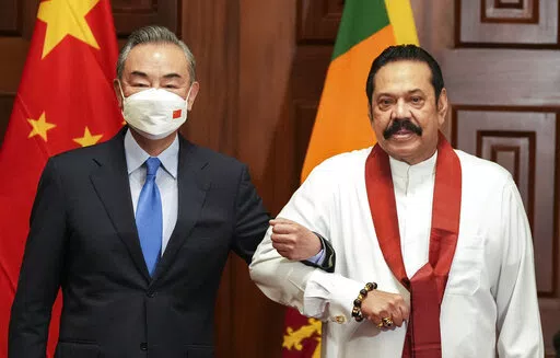 Chinese Foreign Minister Wang Yi, left, poses for media before his meeting with Sri Lankan Prime Minister Mahinda Rajapaksa in Colombo, Sri Lanka, Sunday, Jan. 9, 2022. (AP Photo/Eranga Jayawardena)