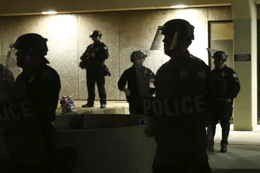 Phoenix Police stand in front of police headquarters on May 30, 2020, in Phoenix, waiting for protesters marching to protest the death of George Floyd. Arizona's governor has signed into law a measure that makes it illegal to knowingly record video of police officers within 8 feet (2.5 meters) or closer without an officer's permission, spurring concerns among civil rights activists about transparency and accountability. (AP Photo/Ross D. Franklin, File)