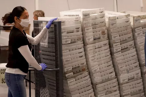 An election worker arrives with ballots to be tabulated inside the Maricopa County Recorders Office, Wednesday, Nov. 9, 2022, in Phoenix. (AP Photo/Matt York)