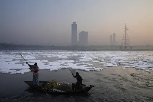 Fishermen row their boat amidst morning smog in the river Yamuna as toxic foam floats in the river ahead of Diwali festival in New Delhi, India, Tuesday, Oct. 29, 2024. (AP Photo/Manish Swarup)