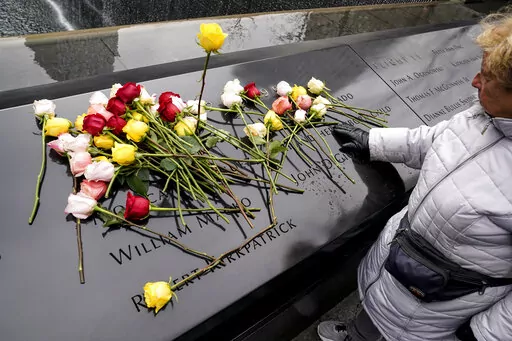 Mourners place flowers over the names of the victims of the 1993 World Trade Center bombing during a ceremony at the 9/11 Memorial, Sunday, Feb. 26, 2023, in New York. (AP Photo/John Minchillo)