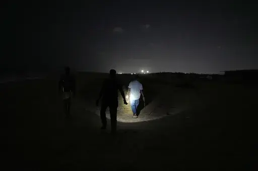 A forest official walks with volunteers to search for olive ridley sea turtle eggs on Marina Beach in Chennai, India, Thursday, March 13, 2025. (AP Photo/Mahesh Kumar A.)