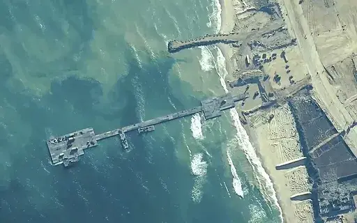 The image provided by U.S, Central Command, shows U.S. Army soldiers assigned to the 7th Transportation Brigade (Expeditionary), U.S. Navy sailors assigned to Amphibious Construction Battalion 1, and Israel Defense Forces placing the Trident Pier on the coast of Gaza Strip on May 16, 2024. A U.S. built temporary pier that had been used to deliver additional humanitarian aid into Gaza was damaged by rough seas and has temporarily suspended operations. That’s according to three U.S. officials wh