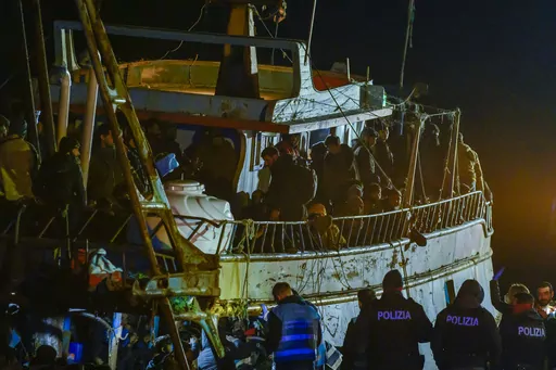 Police check a fishing boat with some 500 migrants in the southern Italian port of Crotone, early Saturday, March 11, 2023. The Italian coast guard was responding to three smugglers boats carrying more than 1,300 migrants “in danger” off Italy’s southern coast, officials said Friday. Three small coast guard boats were rescuing a boat with 500 migrants about 700 miles off the Calabria region, which forms the toe of the Italian boot. (AP Photo/Valeria Ferraro)