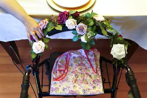 A woman holds onto the walker once belonging to her mother who died of COVID-19 while at a nursing home, as her family prays before Thanksgiving dinner, Nov. 26, 2020, in Deer Park, N.Y. A sobering study out Wednesday, April 6, 2022, from the National Academies of Sciences, Engineering, and Medicine is calling for wholesale changes in the U.S. long-term care system in the wake of more than 150,000 resident COVID-19 deaths. (AP Photo/John Minchillo, File)